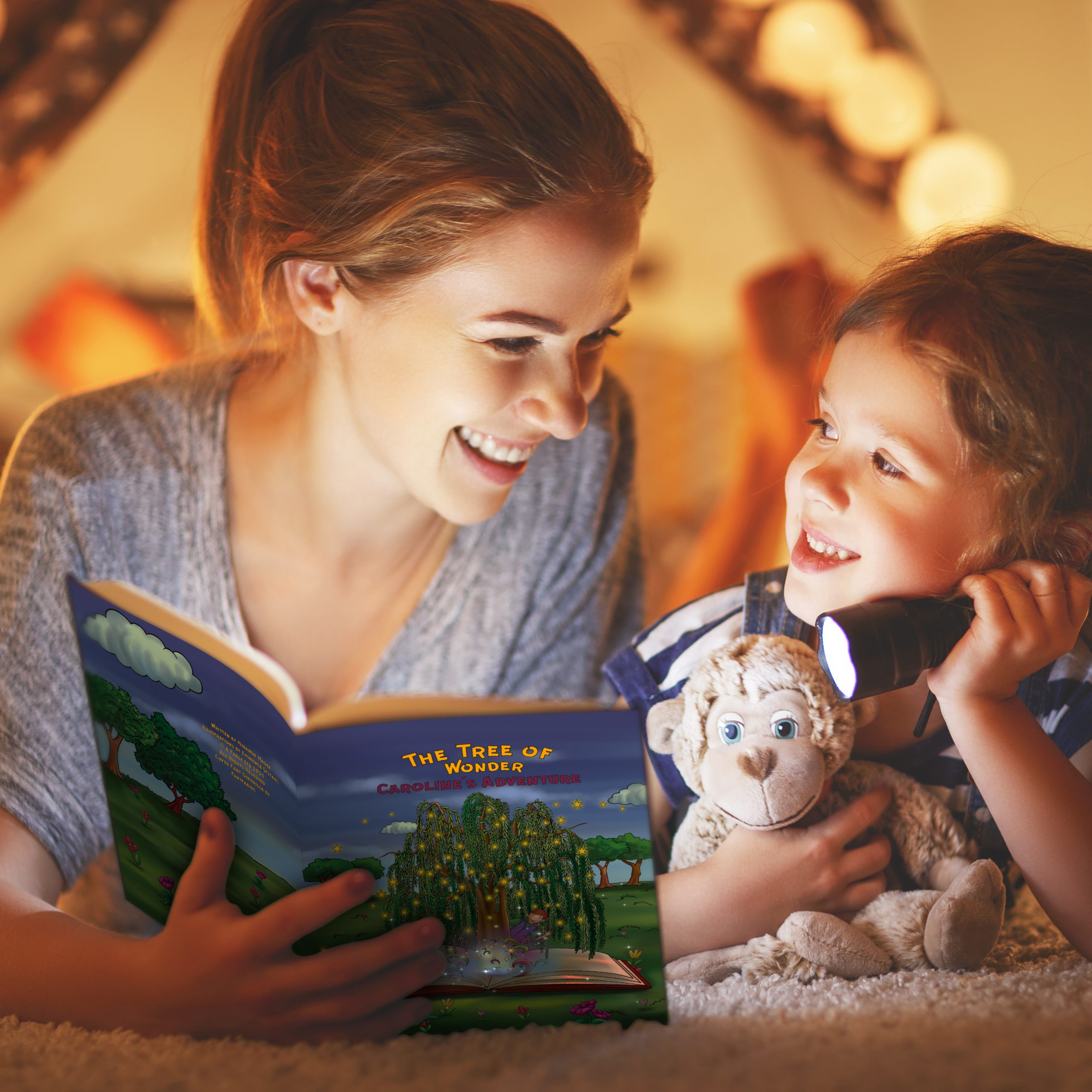 mother and child daughter reading a book and a flashlight before going to bed